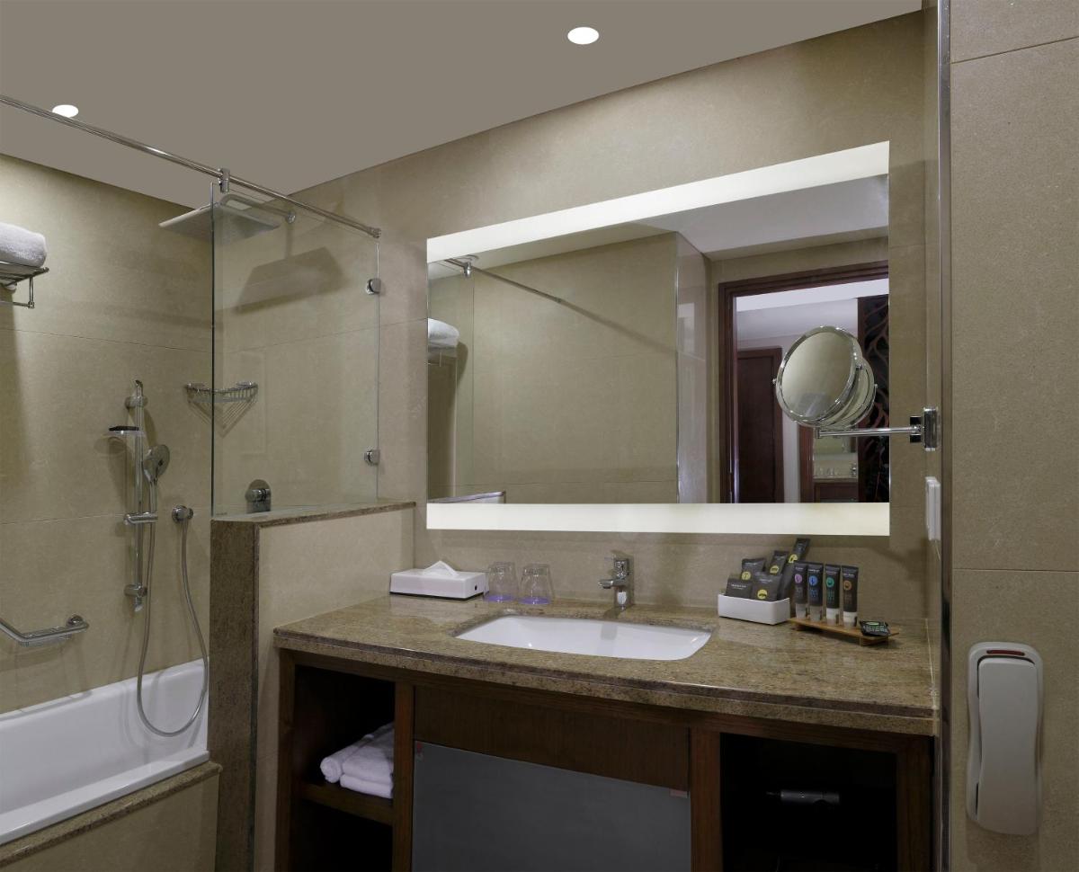 a bathroom with a sink and a shower and a mirror at Novotel Kochi Infopark in Cochin