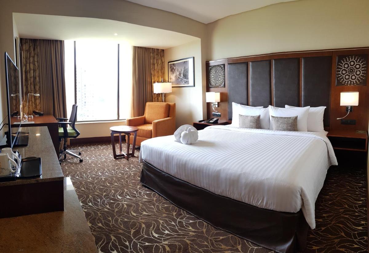 a hotel room with a large bed and a desk at Novotel Kochi Infopark in Cochin