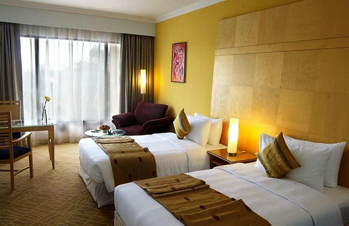 a hotel room with two beds and a chair at The Chancery Pavilion in Bengaluru