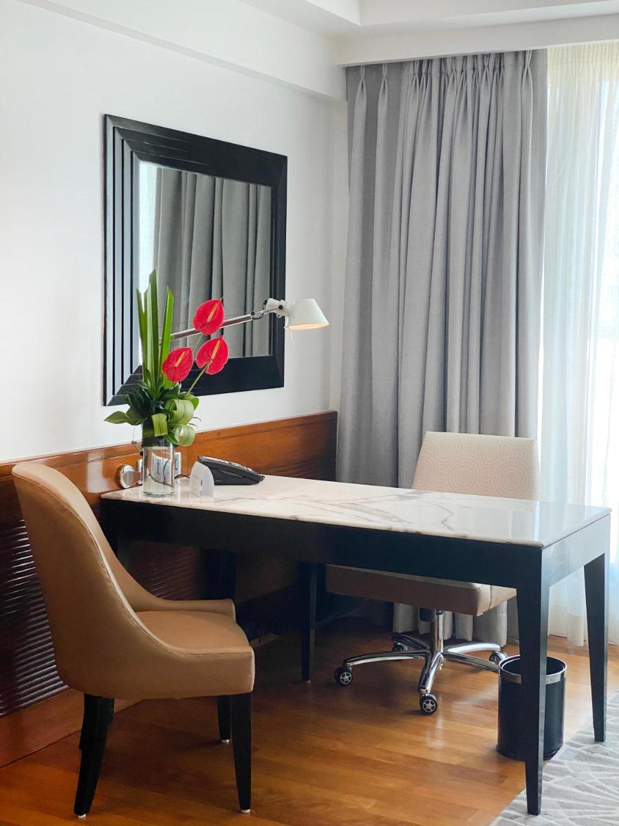 a desk with two chairs and a vase of red flowers at InterContinental Marine Drive Mumbai by IHG in Mumbai