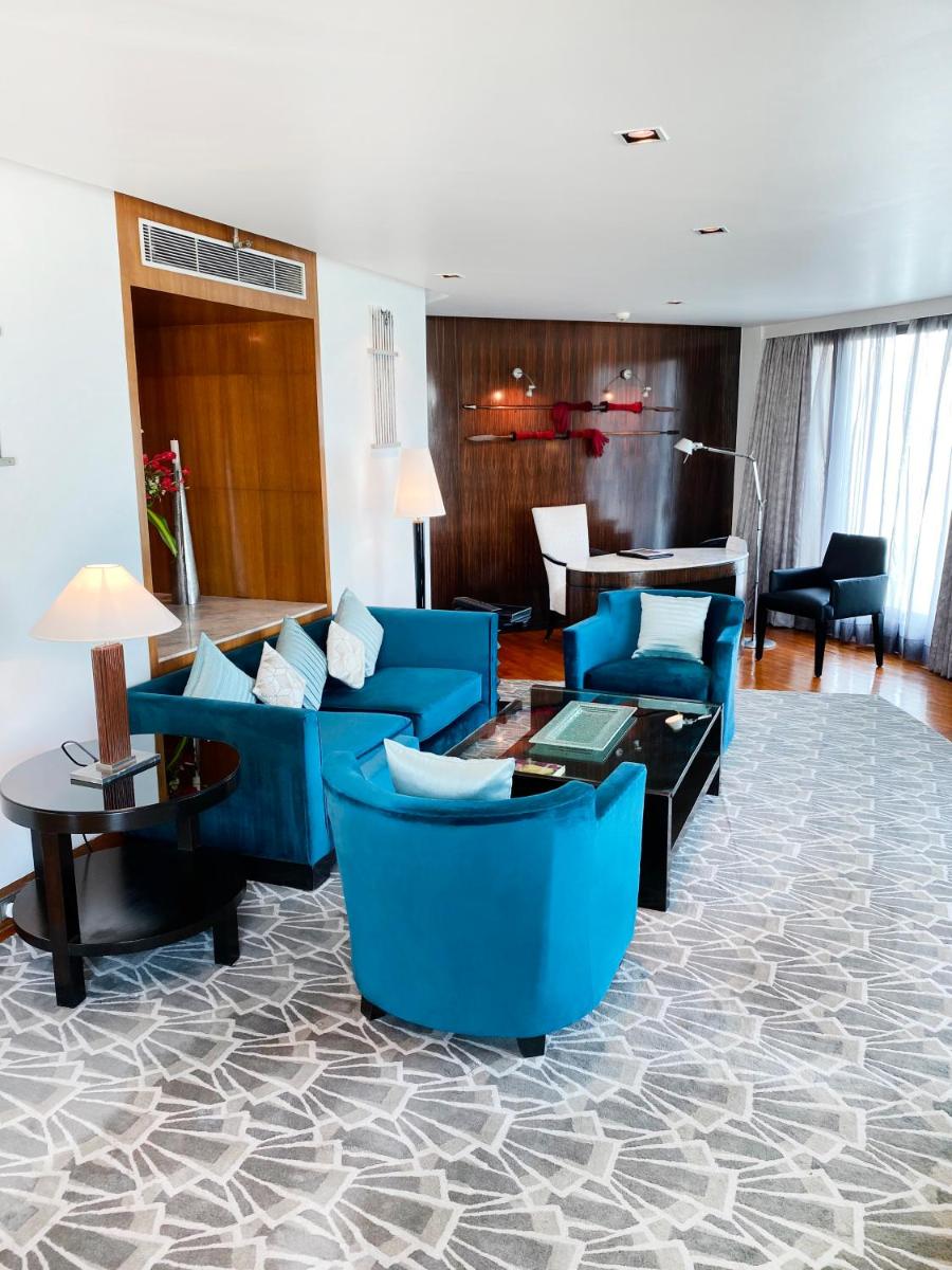 a living room with blue furniture and a piano at InterContinental Marine Drive Mumbai by IHG in Mumbai