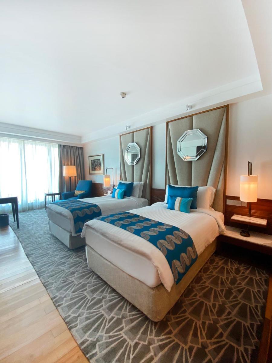 two beds in a hotel room with blue pillows at InterContinental Marine Drive Mumbai by IHG in Mumbai