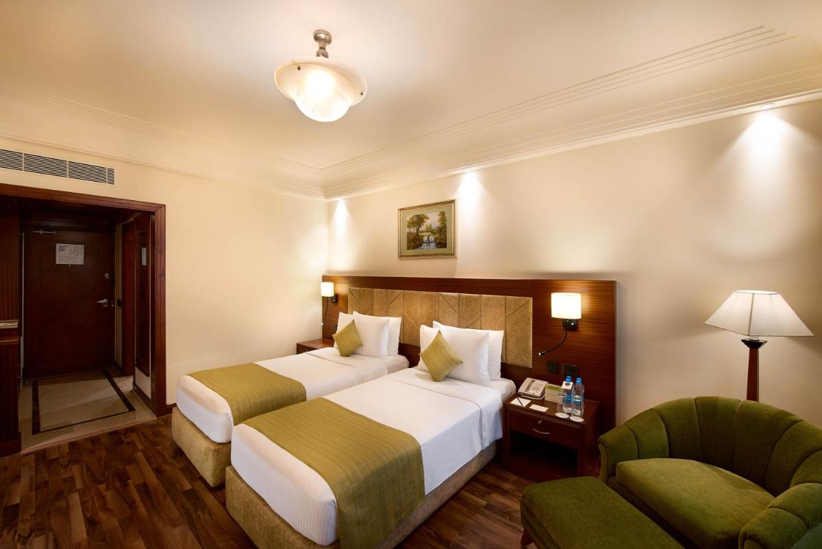 a hotel room with two beds and a chair at The Accord Metropolitan in Chennai