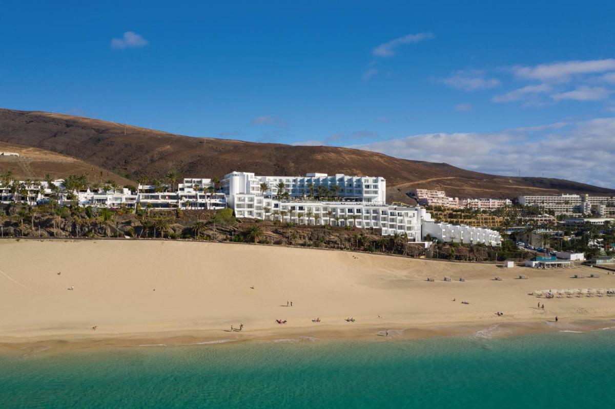 Un grupo de personas en una playa con edificios. en Hotel Riu Palace Jandia, en Playa de Jandía