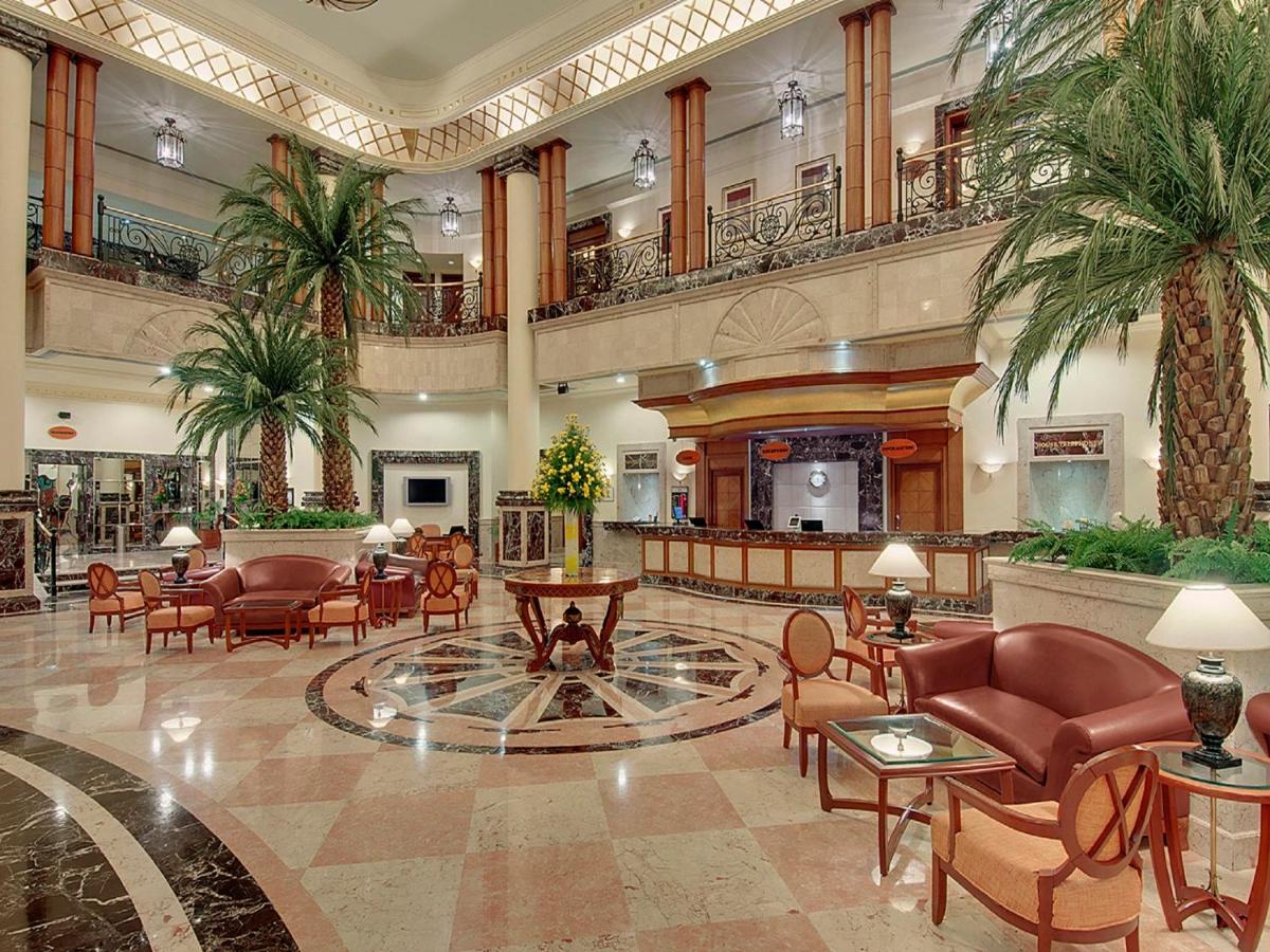 a lobby with chairs and tables and palm trees at The Residency Towers in Chennai