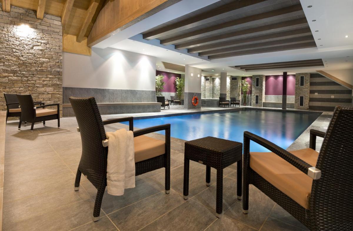 - une piscine avec des chaises et une table dans un bâtiment dans l'établissement CGH Résidence Boutique Le Chalet des Dolines, à Montgenèvre