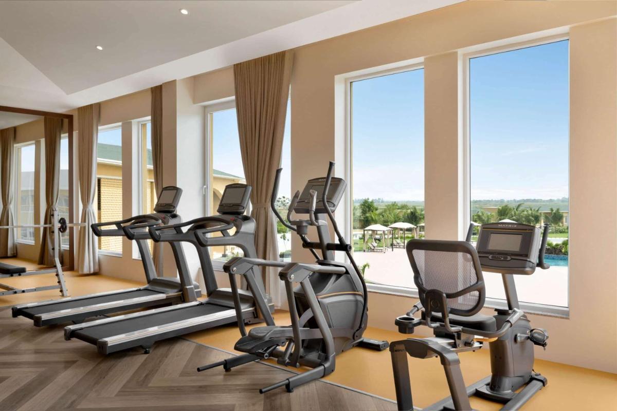 a gym with treadmills and elliptical machines at Hawthorn Suites by Wyndham Dwarka in Dwarka a gym with treadmills and elliptical machines at Hawthorn Suites by Wyndham Dwarka in Dwarka