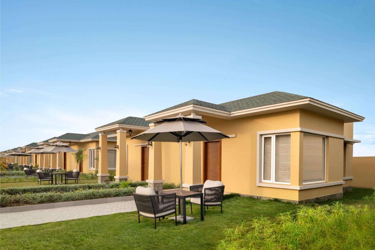 a house with a table and chairs and an umbrella at Hawthorn Suites by Wyndham Dwarka in Dwarka a house with a table and chairs and an umbrella at Hawthorn Suites by Wyndham Dwarka in Dwarka