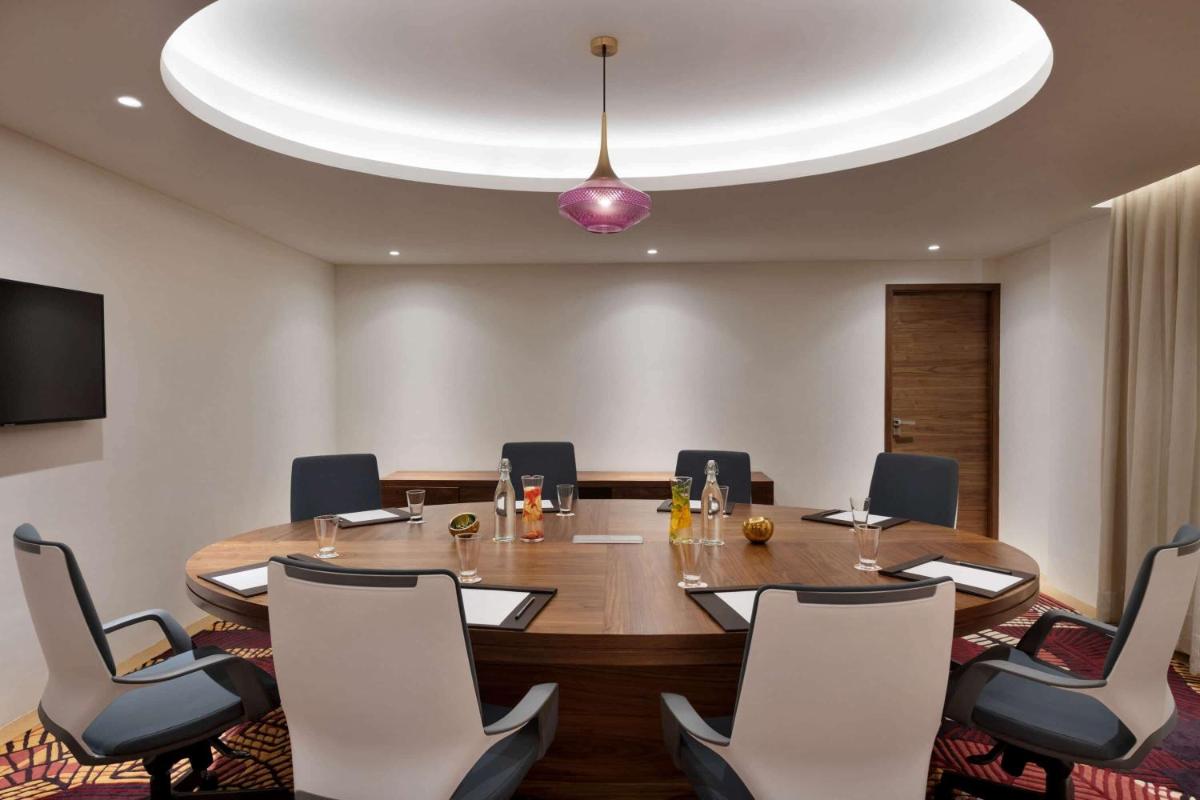 a conference room with a large wooden table and chairs at Hawthorn Suites by Wyndham Dwarka in Dwarka a conference room with a large wooden table and chairs at Hawthorn Suites by Wyndham Dwarka in Dwarka