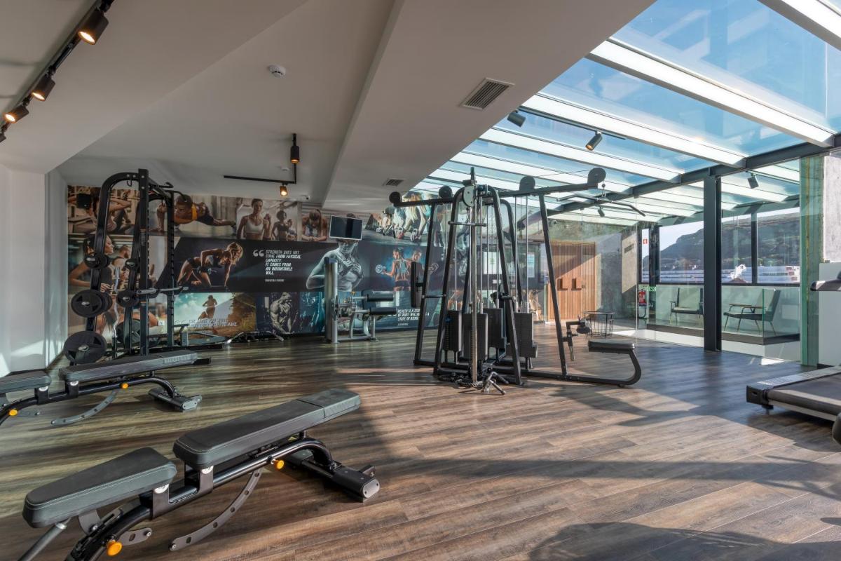 uma academia com esteiras e equipamentos de ginástica em um prédio em Well Hotel & Spa em Maceira