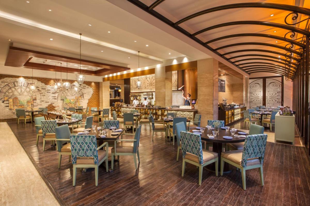 a dining room with tables and chairs in a restaurant at Hyatt Regency Pune Hotel & Residences in Pune