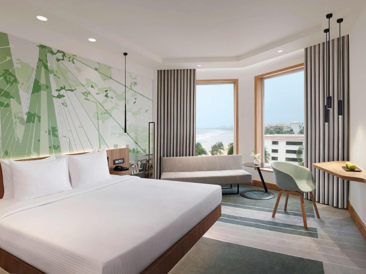 a bedroom with a bed and a living room at Novotel Mumbai Juhu Beach in Mumbai