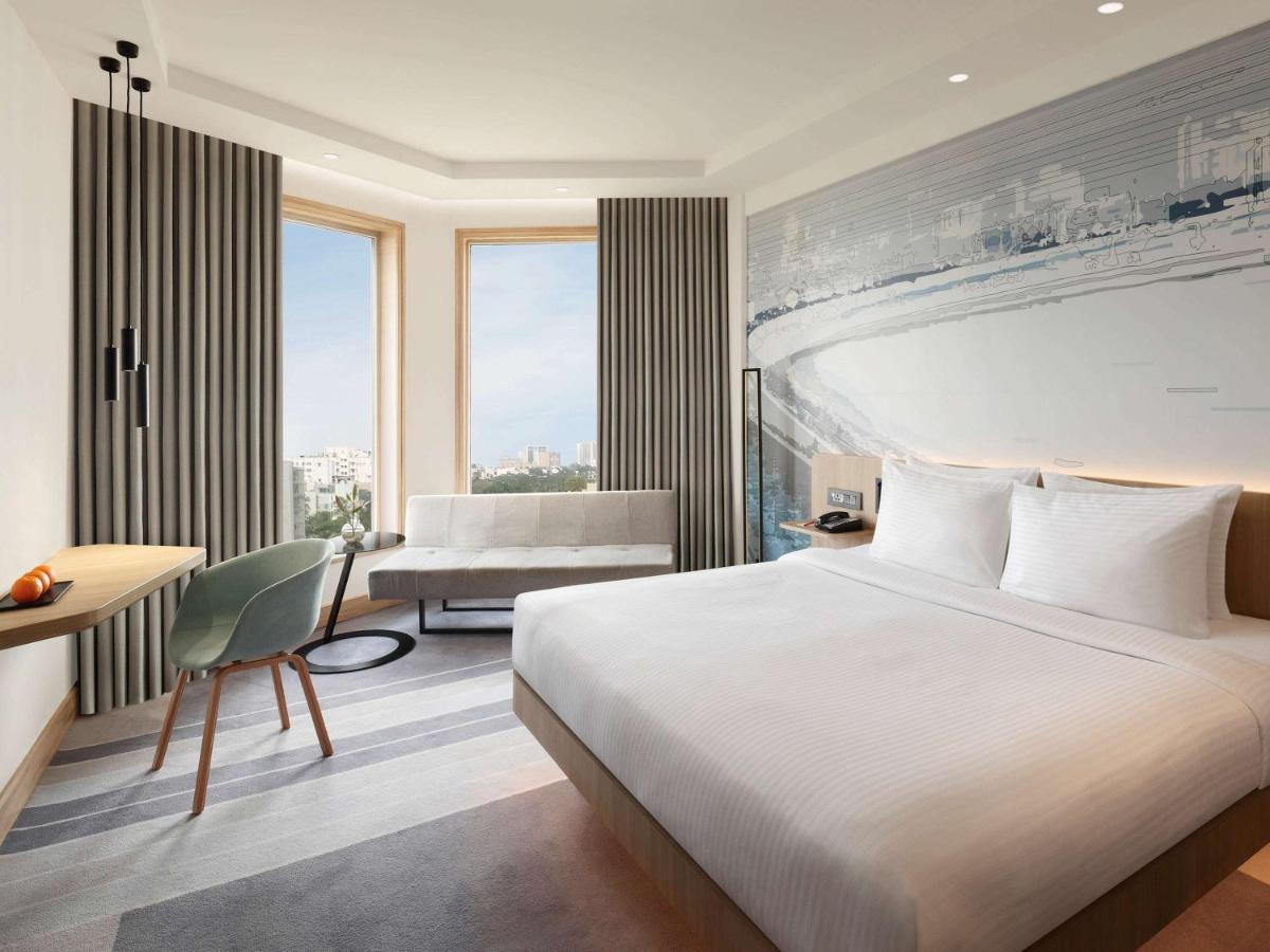 a hotel room with a bed and a desk and a bedroom at Novotel Mumbai Juhu Beach in Mumbai
