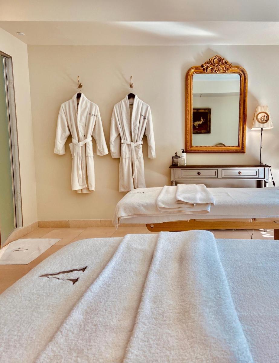 - une chambre avec des peignoirs suspendus au mur et un miroir dans l'établissement Le Vallon de Valrugues Hotel Spa & Villas, à Saint-Rémy-de-Provence