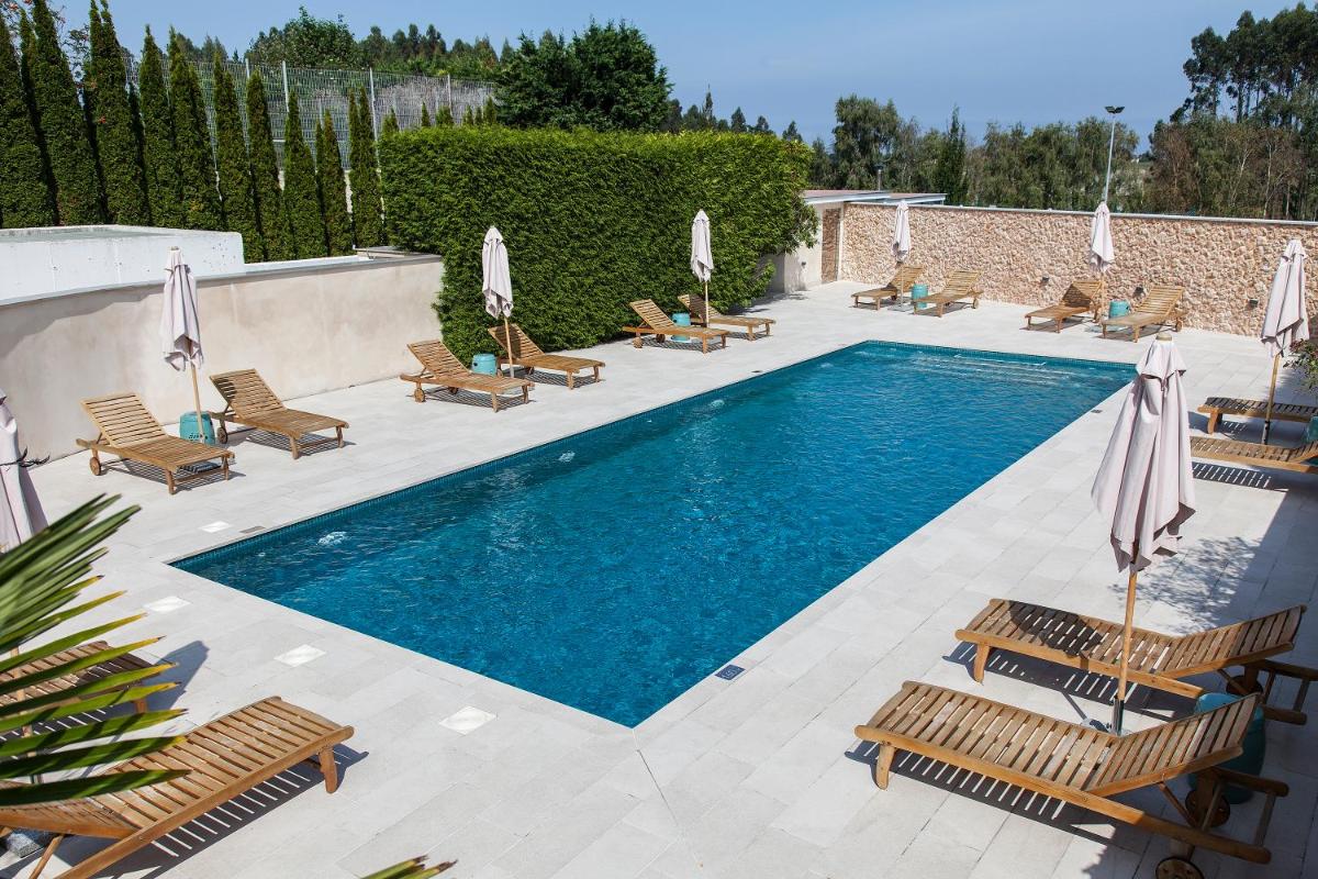 una piscina con tumbonas y sombrillas en Blanco Hotel Spa, en Navia