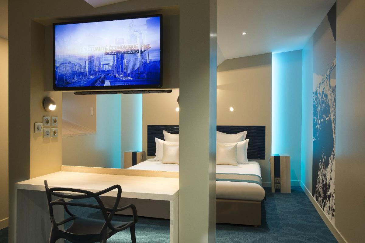 Cette chambre comprend un lit et une télévision murale. dans l'établissement Hôtel Brésil Opéra SPA, à Paris
