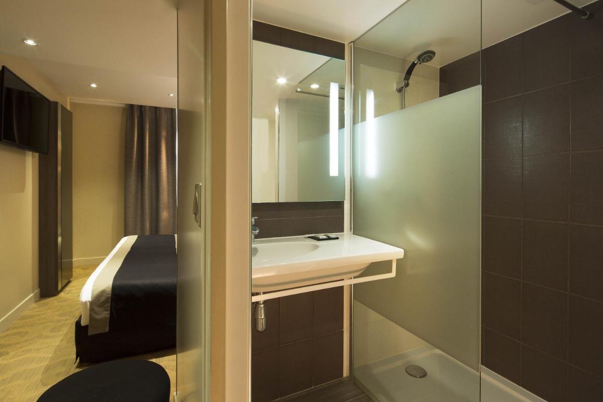 une salle de bain avec un lavabo et un miroir dans l'établissement Hôtel Brésil Opéra SPA, à Paris