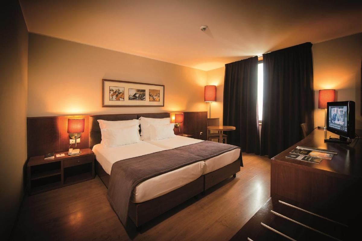 um quarto de hotel com uma cama e uma televisão em Vila Gale Opera em Lisboa