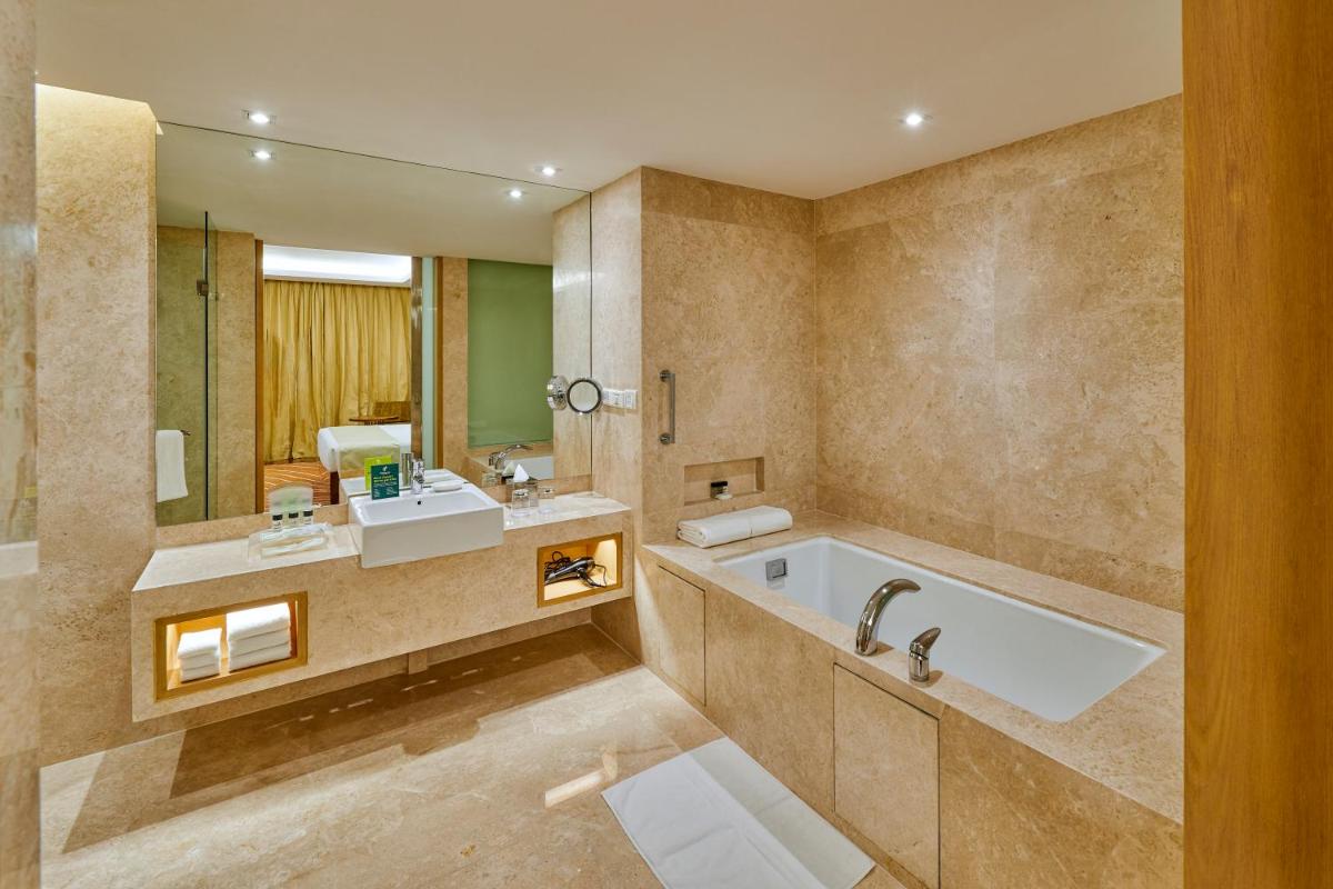 a bathroom with a tub and a sink and a mirror at Holiday Inn Mumbai International Airport by IHG in Mumbai
