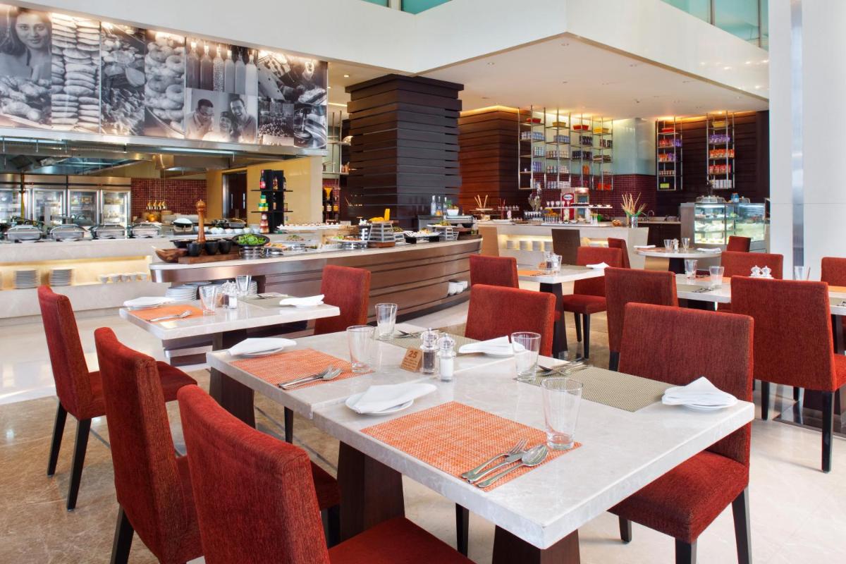 a restaurant with white tables and red chairs at Holiday Inn Mumbai International Airport by IHG in Mumbai