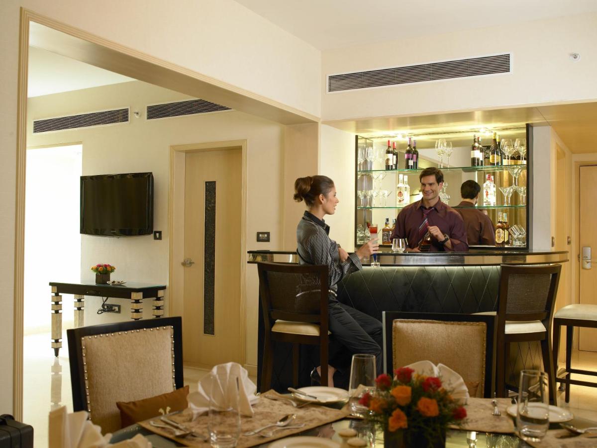 a man and woman sitting at a bar in a restaurant at The Zuri Whitefield Bengaluru in Bengaluru
