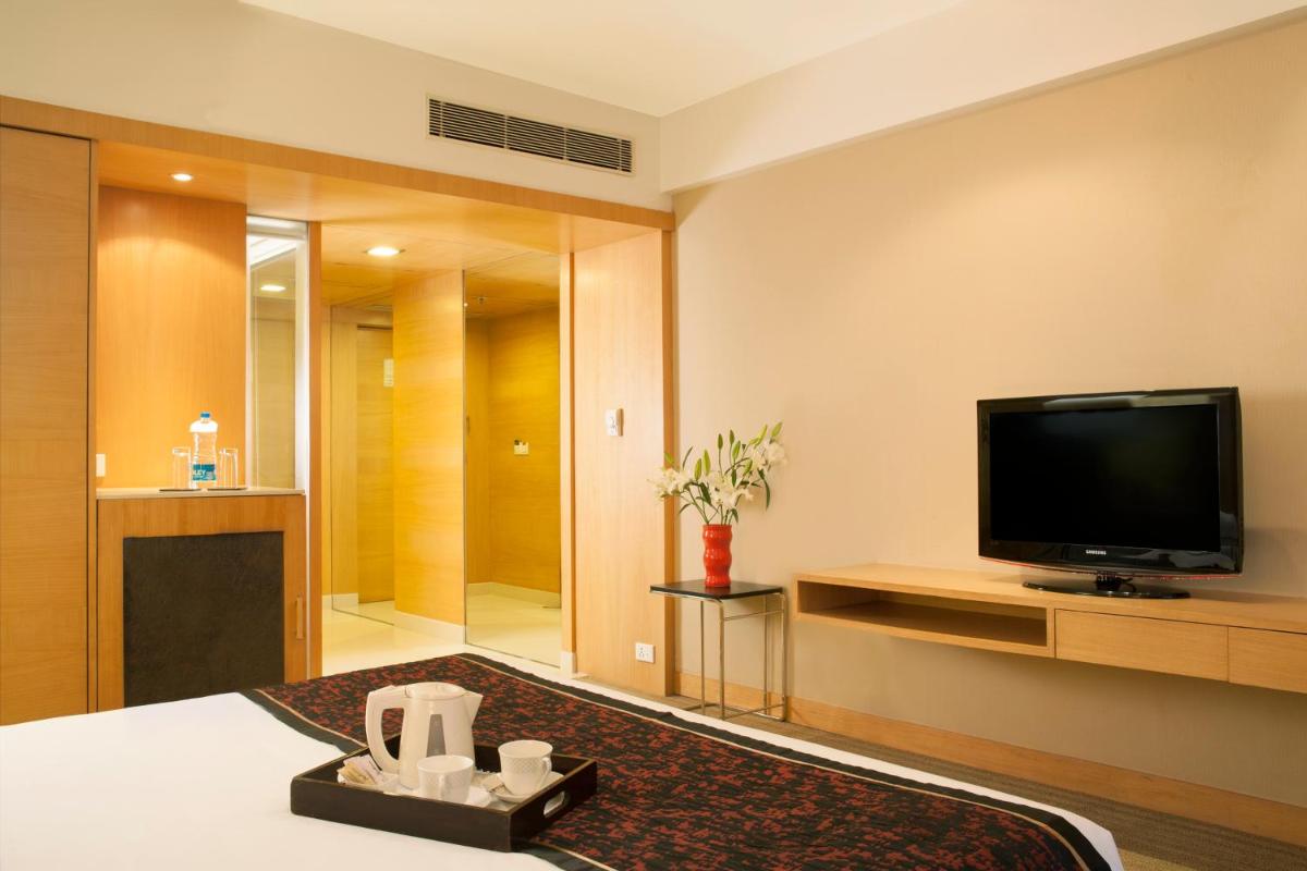 a hotel room with a television and a living room at Radisson Blu Hotel Pune Kharadi in Pune