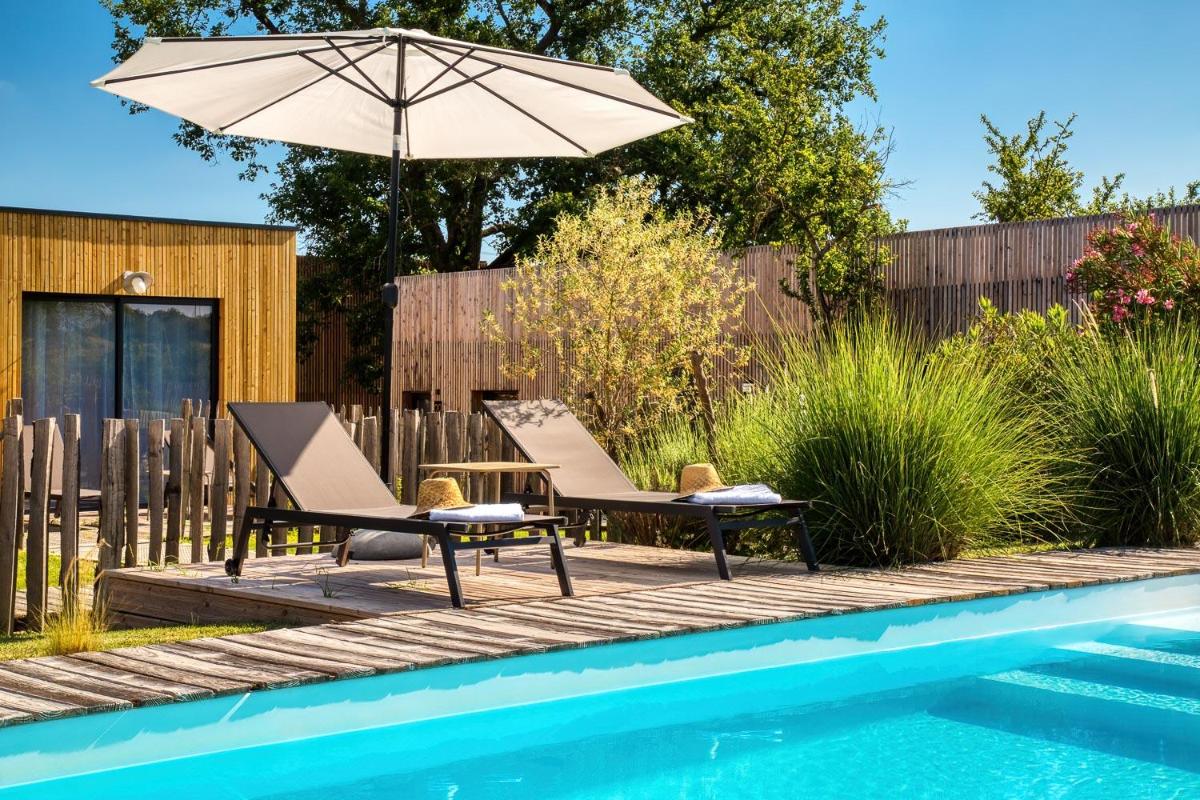 un patio avec deux chaises et un parasol à côté d'une piscine dans l'établissement Le Domaine de Baulieu, Singuliers Hotels, à Auch