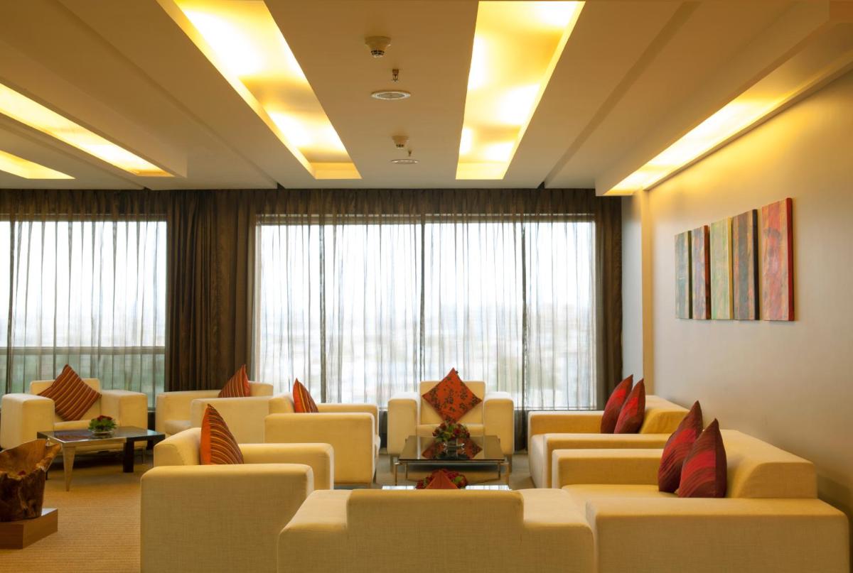 a waiting room with white couches and windows at Radisson Blu Hotel Pune Kharadi in Pune