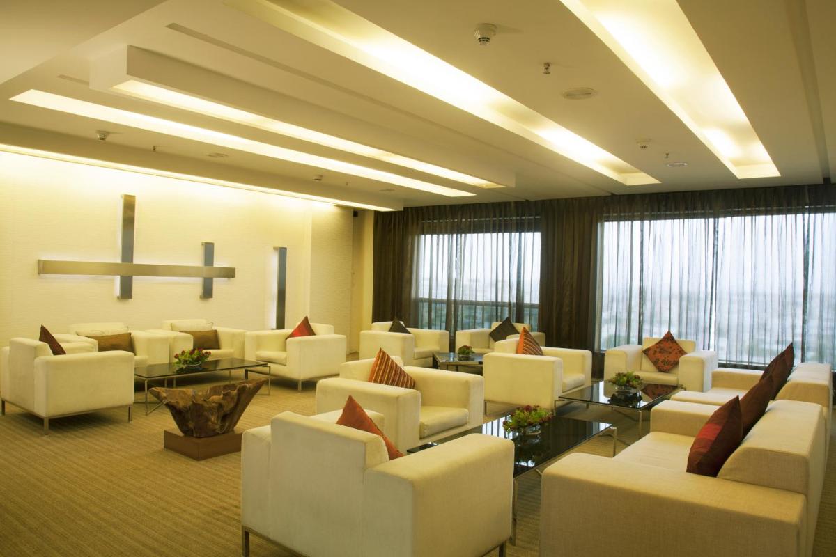 a waiting room with white chairs and tables and windows at Radisson Blu Hotel Pune Kharadi in Pune