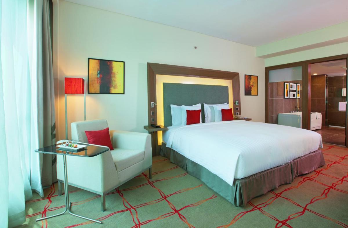 a bedroom with a large bed and a chair at Novotel Ahmedabad in Ahmedabad