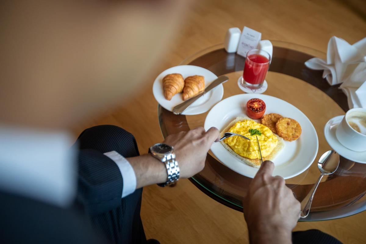 a person sitting at a table with a plate of food at The Orchid Hotel Mumbai Vile Parle in Mumbai