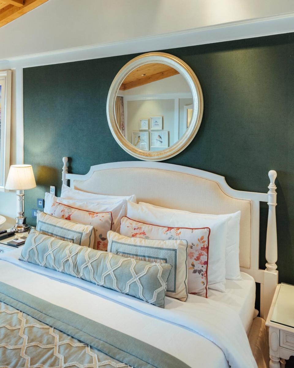 a bedroom with a large white bed with a mirror at Welcomhotel by ITC Hotels, The Savoy, Mussoorie in Mussoorie