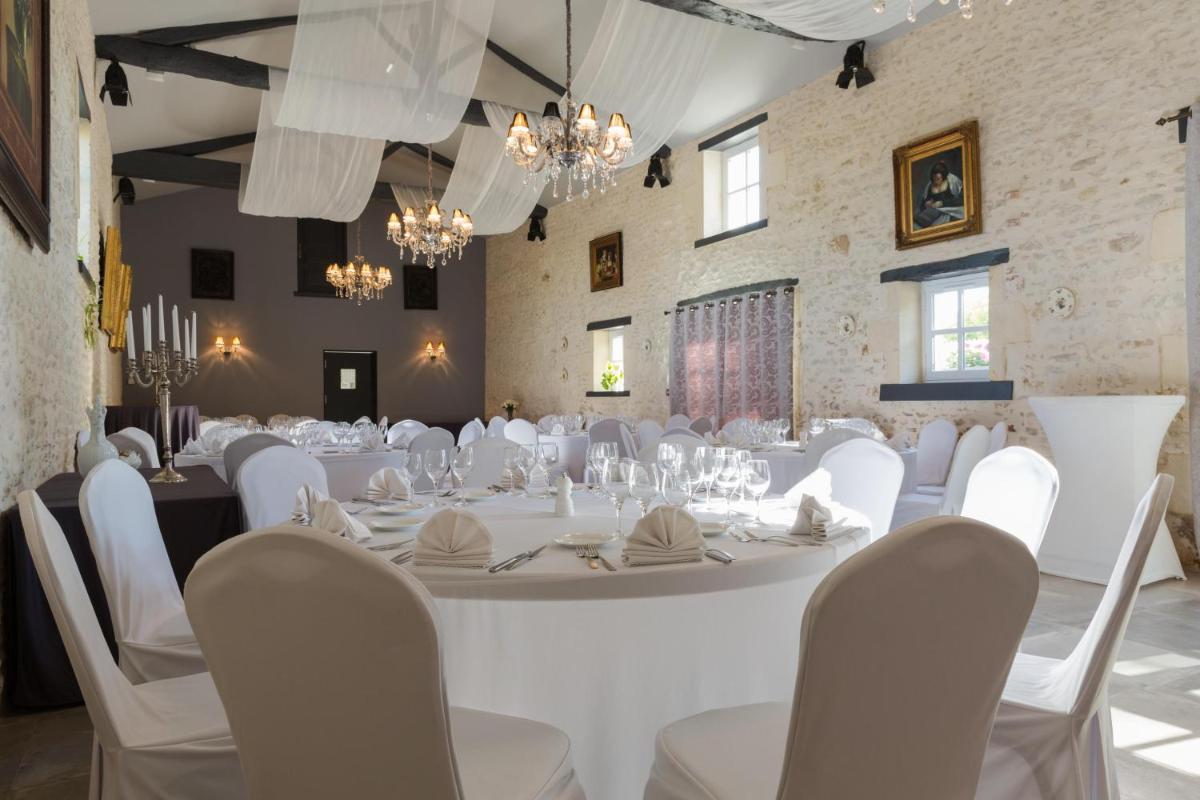 une salle de banquet avec des tables blanches, des chaises et des lustres dans l'établissement Le Logis du Péré, à Saint-Coutant-le-Grand
