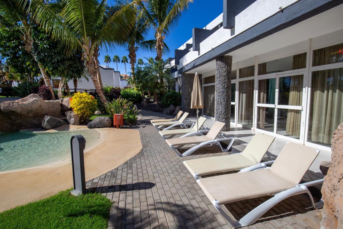 Una fila de tumbonas junto a una piscina. en R2 Romantic Fantasia Suites - Adults Only, en Tarajalejo