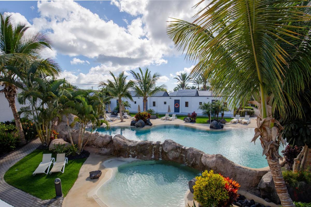 una piscina infinita con cascada en un complejo en R2 Romantic Fantasia Suites - Adults Only, en Tarajalejo