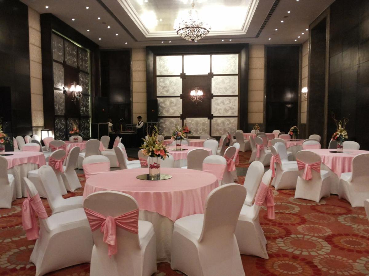 a banquet hall with pink and white tables and chairs at The Pllazio Hotel in Gurgaon