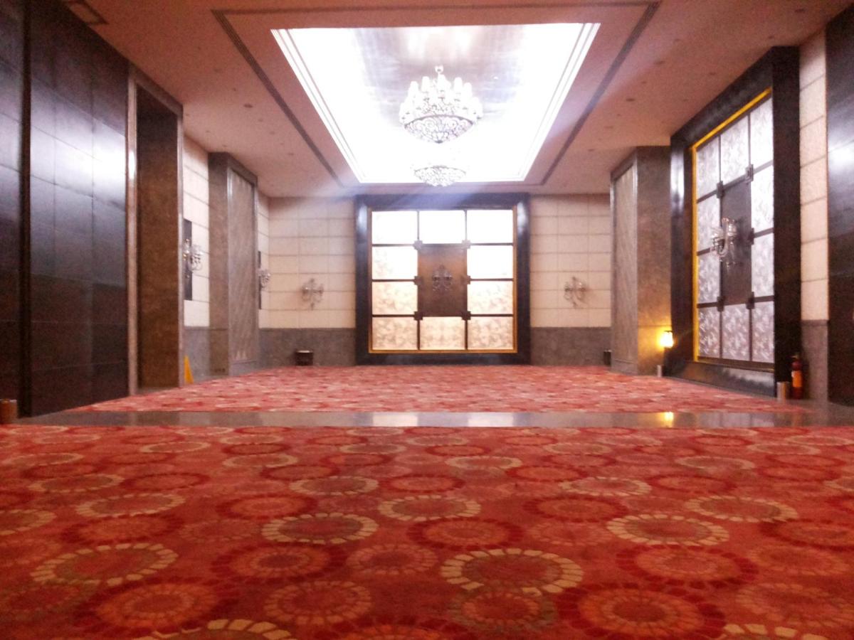 a large room with a chandelier and a large rug at The Pllazio Hotel in Gurgaon