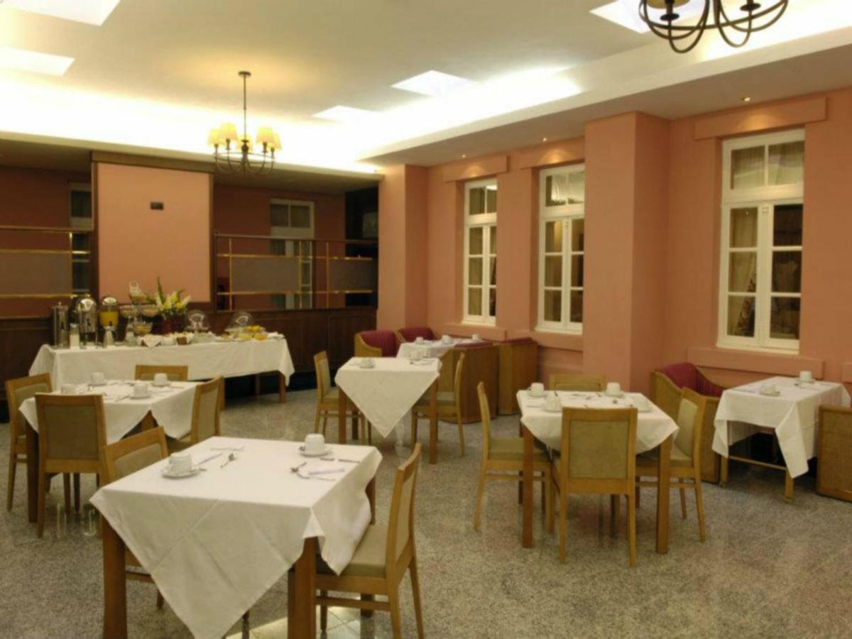 um restaurante com mesas e cadeiras com toalha de mesa branca em Palace Hotel & Spa - Termas de Sao Vicente em Penafiel