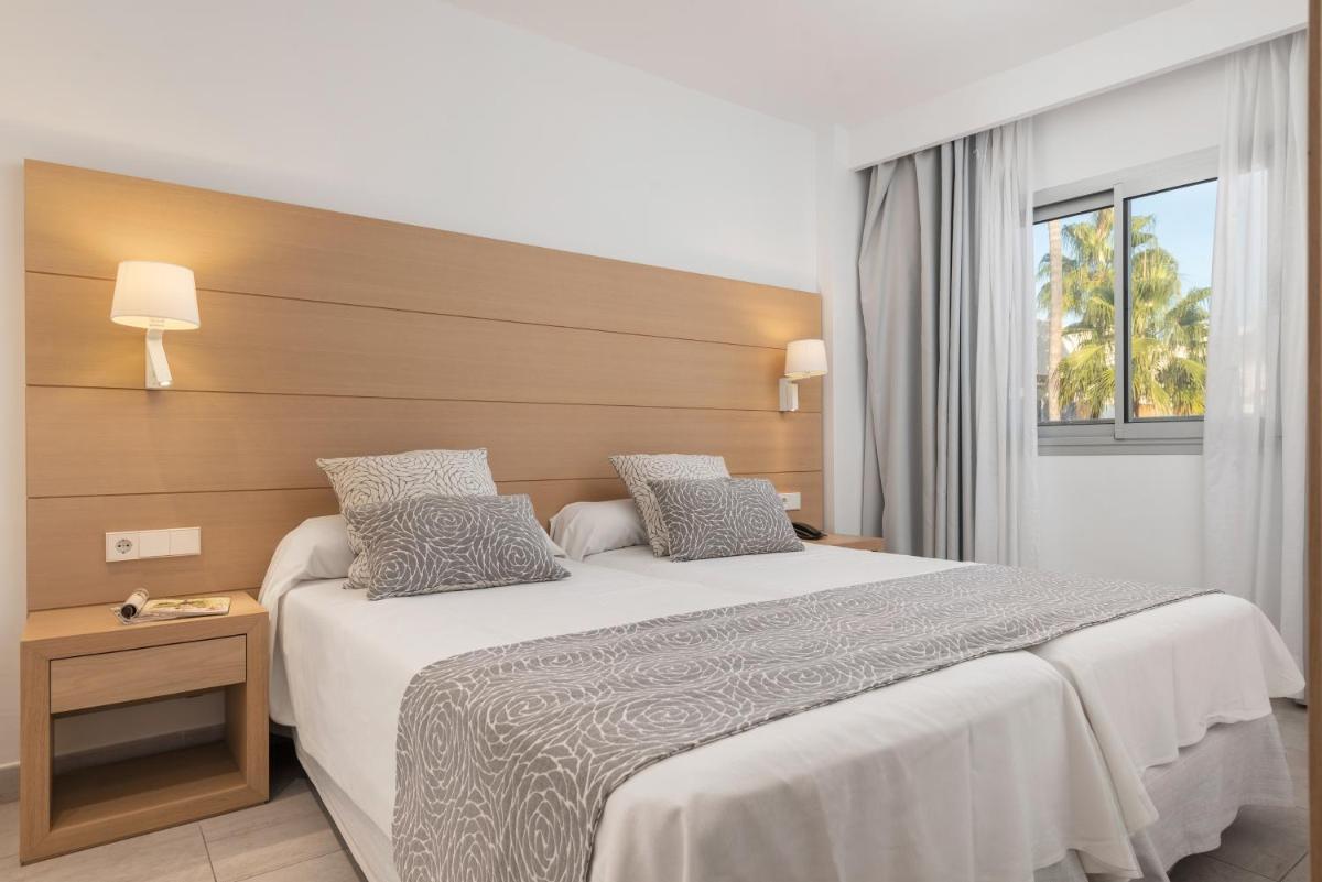 Un dormitorio con una cama grande con cabecero de madera. en Trendhotel Alcudia - Adults Only, en Puerto de Alcudia