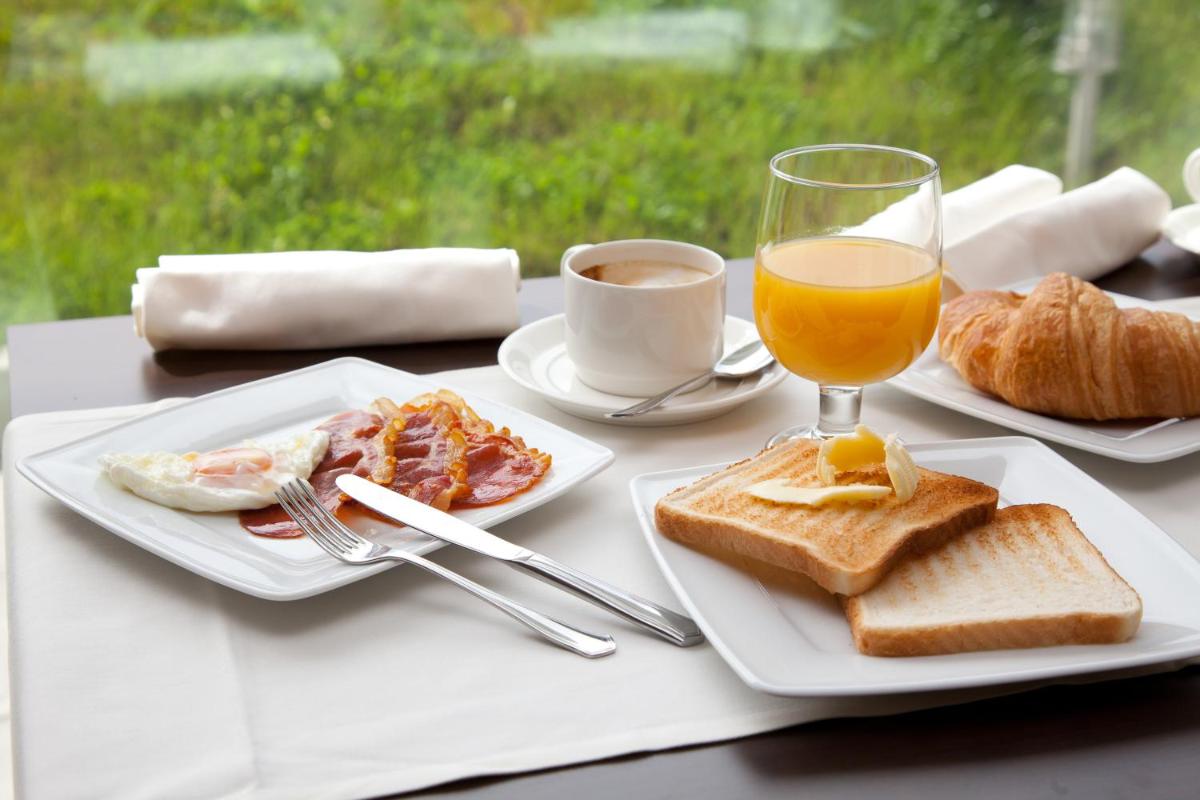 una mesa con dos platos de comida y un vaso de jugo de naranja en Hotel Las Sirenas, en Viveiro