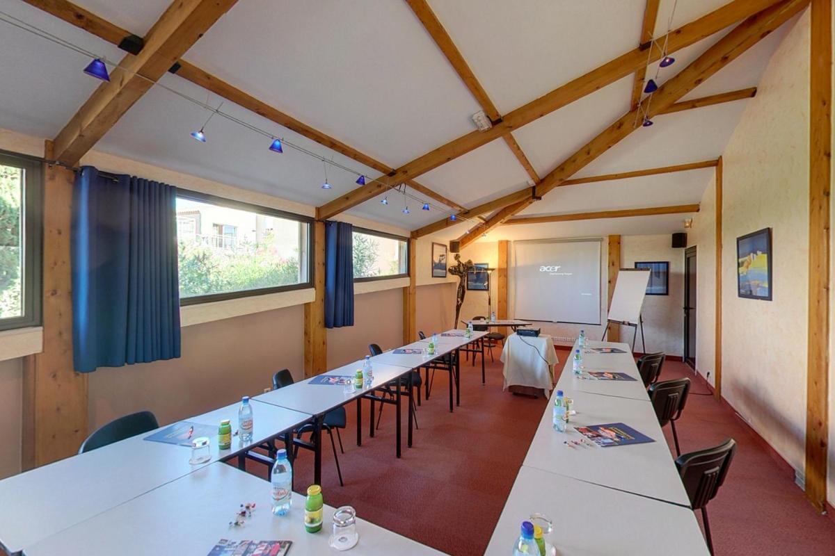 une salle de classe avec de longues tables et chaises et un tableau blanc dans l'établissement Hotel Le Phoebus Garden & Spa, à Gruissan