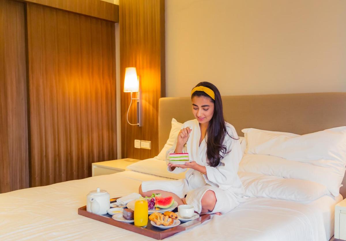 a woman sitting on a bed with a tray of food at Hyatt Regency Delhi in New Delhi a woman sitting on a bed with a tray of food at Hyatt Regency Delhi in New Delhi