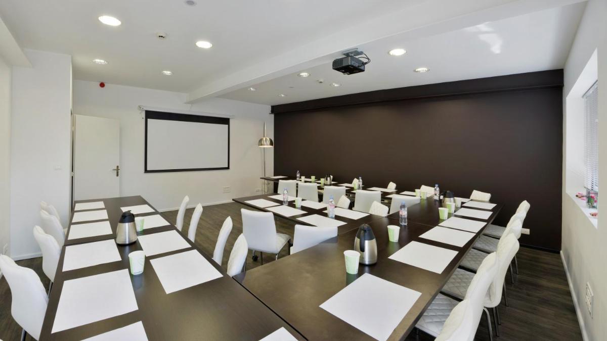 une salle de conférence avec une longue table et des chaises blanches dans l'établissement Logis - Hôtel Arc en Ciel et SPA Les Sables d'Olonne, à Les Sables-dʼOlonne