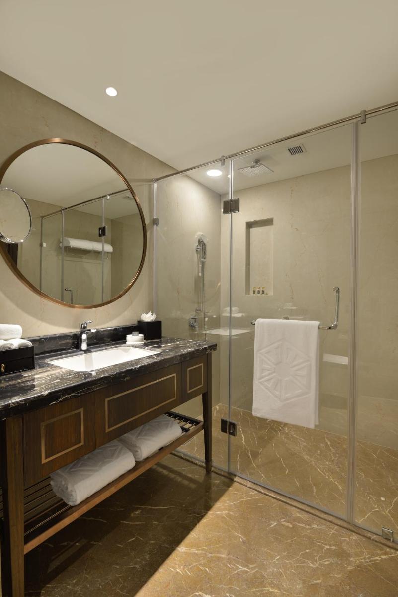 a bathroom with a sink and a shower with a mirror at Taj Skyline Ahmedabad in Ahmedabad
