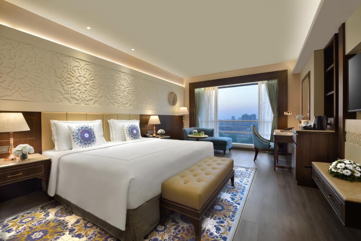 a bedroom with a large white bed and a desk at Taj Skyline Ahmedabad in Ahmedabad