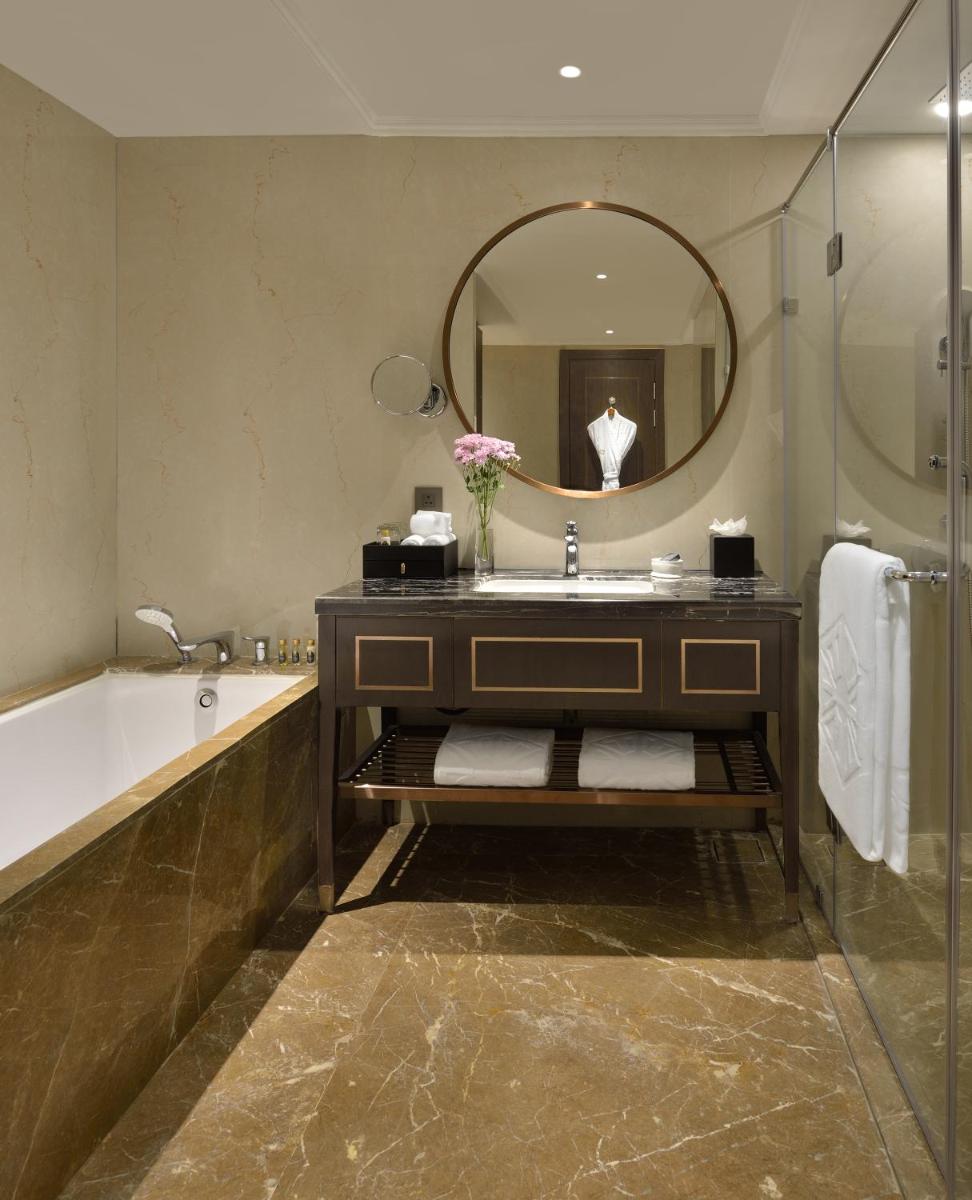 a bathroom with a tub and a sink and a mirror at Taj Skyline Ahmedabad in Ahmedabad