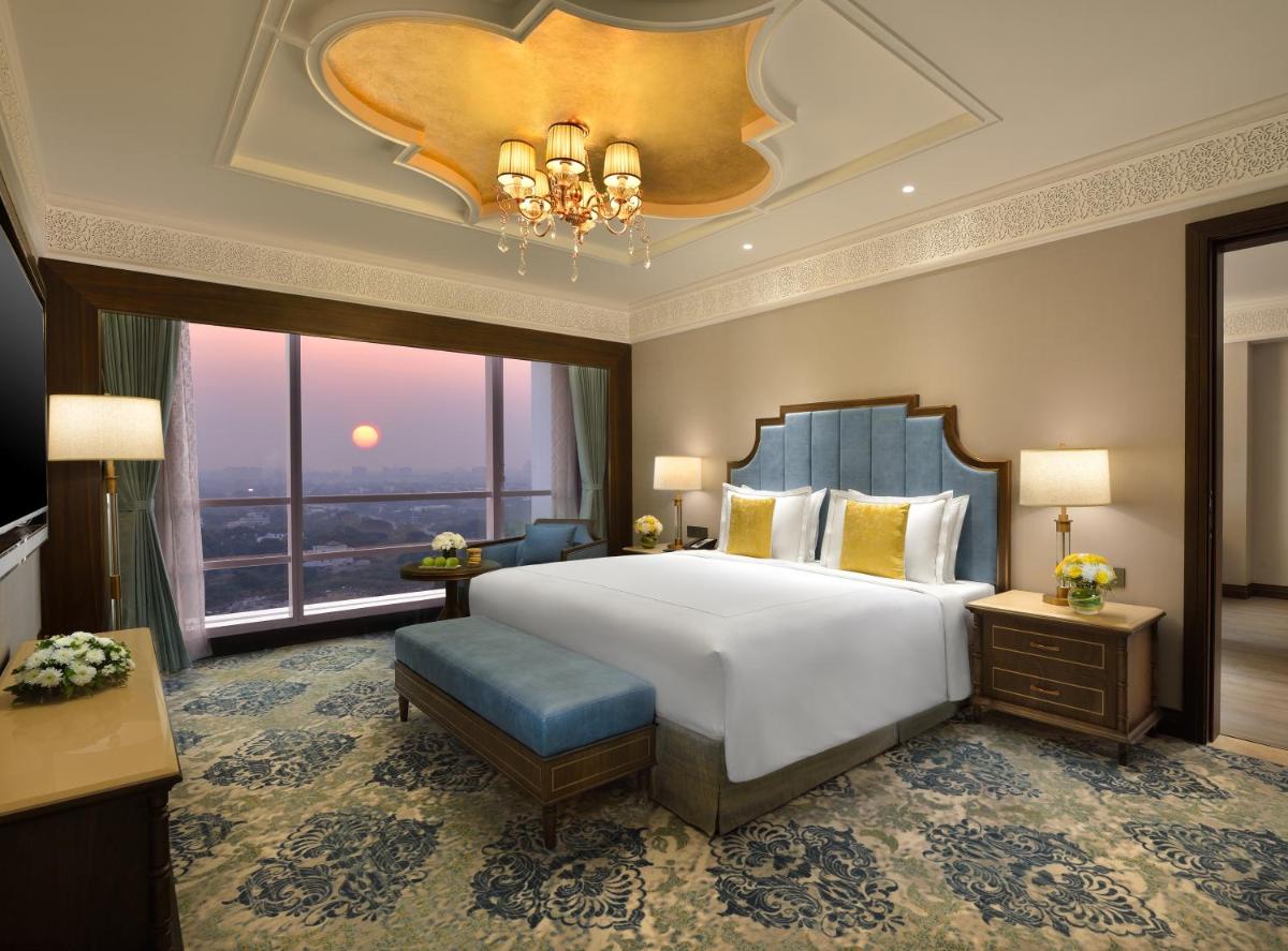 a bedroom with a large bed and a large window at Taj Skyline Ahmedabad in Ahmedabad
