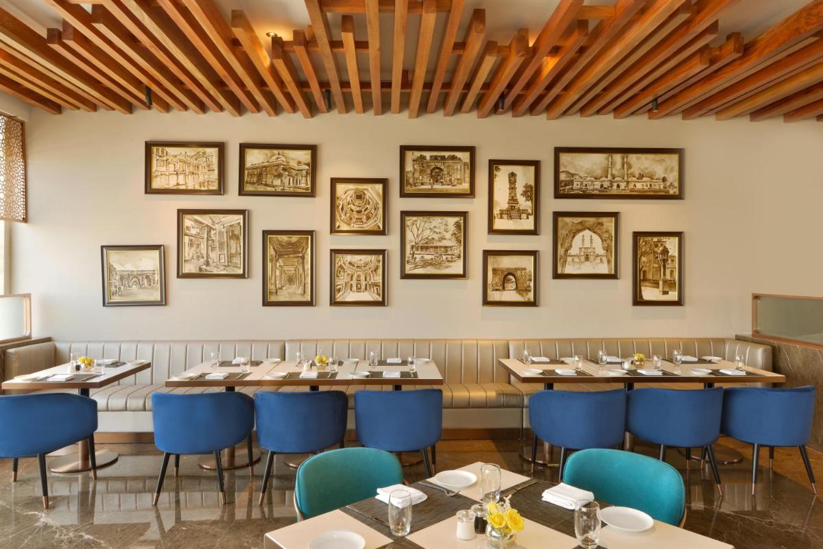 a dining room with tables and blue chairs at Taj Skyline Ahmedabad in Ahmedabad