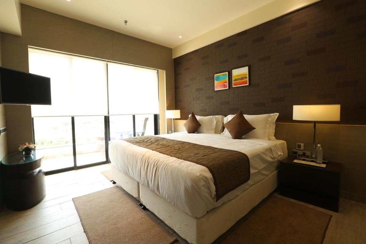 a bedroom with a large bed and a large window at Wyndham Ahmedabad Shela in Ahmedabad