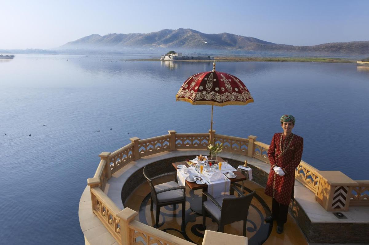 a woman standing in front of a table with an umbrella at The Leela Palace Udaipur in Udaipur
